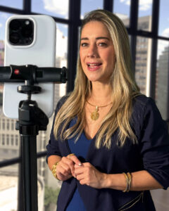 Mulher loira apresentando em frente ao smartphone em tripé para gravação de vídeo corporativo em escritório